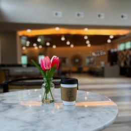 a cup of coffee and flowers on a table